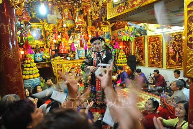 Trong ảnh: Thanh Đồng ban phát cho những người xung quanh tiền lộc và những người đứng xem xung quanh nhặt lấy cất giữ để lấy may. Ảnh: Minh Đức – TTXVN

