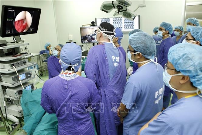 Trong ảnh: Chuyên gia phẫu thuật chỉnh hình Pháp trực tiếp hỗ trợ kỹ thuật cho kíp phẫu thuật nội soi khớp vai do chấn thương trong thể thao được truyền hình trực tiếp từ phòng mổ Bệnh viện Hữu nghị Việt Đức đến 18 điểm cầu các bệnh viện tuyến tỉnh. Ảnh: Dương Ngọc-TTXVN