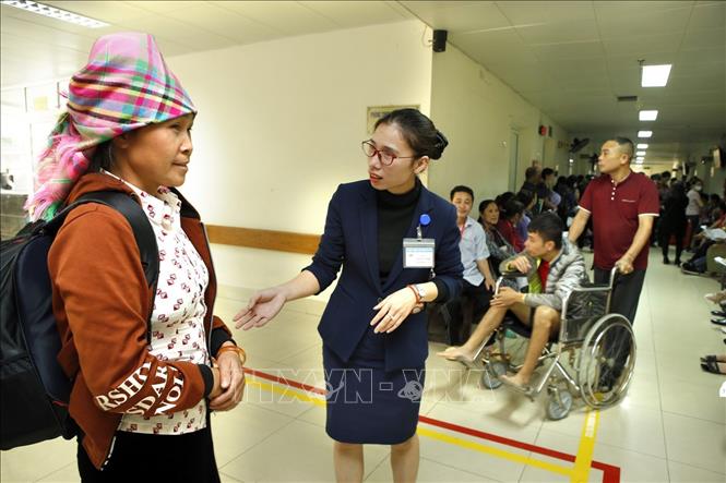 Trong ảnh: Nhân viên công tác xã hội hướng dẫn người bệnh làm thủ tục khám chữa bệnh tại bệnh viện Hữu nghị Việt Đức. Ảnh: Dương Ngọc - TTXVN