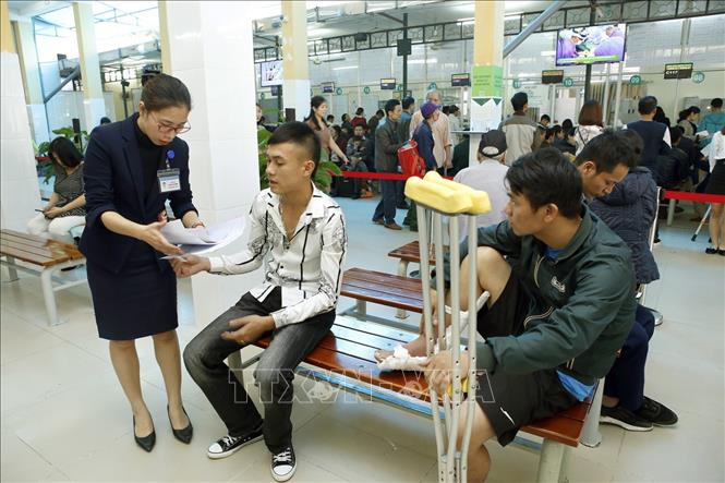 Trong ảnh: Nhân viên công tác xã hội hướng dẫn người bệnh làm thủ tục khám chữa bệnh tại bệnh viện Hữu nghị Việt Đức. Ảnh: Dương Ngọc - TTXVN