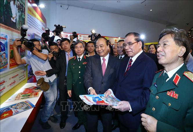 Trong ảnh: Thủ tướng Nguyễn Xuân Phúc, nguyên Tổng Bí thư Nông Đức Mạnh và các đại biểu tham quan gian trưng bày các ấn phẩm của Báo Quân đội nhân dân. Ảnh: Thống Nhất - TTXVN