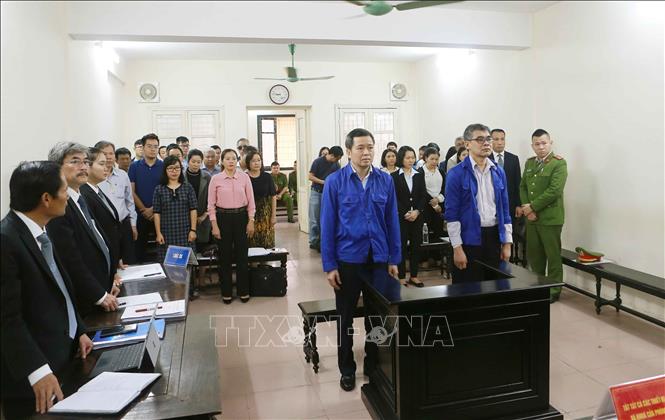 Trong ảnh: Bị cáo Võ Quang Huy (đứng bên trái, sinh năm 1961, nguyên Chánh kế toán VSP) và bị cáo Từ Thành Nghĩa (đứng bên phải, sinh năm 1962, nguyên Tổng Giám đốc VSP) và phiên tòa. Ảnh: Doãn Tấn - TTXVN