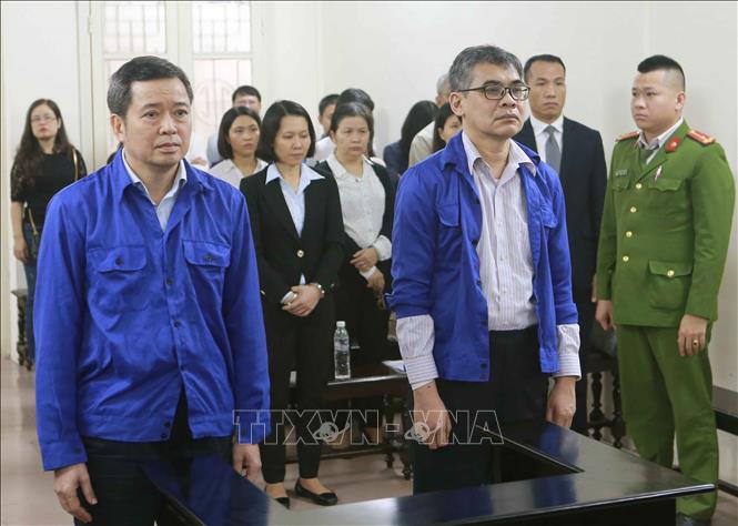 Trong ảnh: Bị cáo Võ Quang Huy (đứng bên trái, sinh năm 1961, nguyên Chánh kế toán VSP) và bị cáo Từ Thành Nghĩa (đứng bên phải, sinh năm 1962, nguyên Tổng Giám đốc VSP) tại phiên tòa. Ảnh: Doãn Tấn - TTXVN