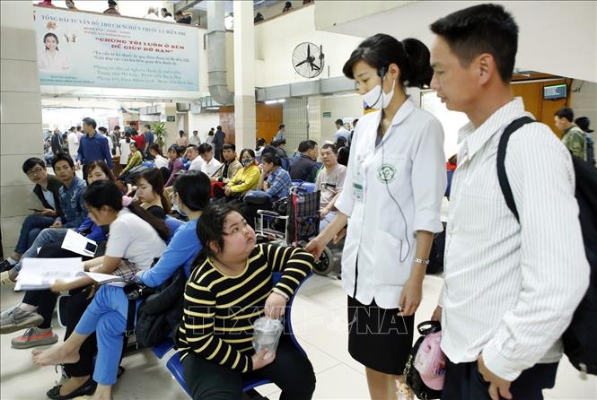 Trong ảnh: Nhân viên công tác xã hội hướng dẫn người bệnh làm thủ tục khám chữa bệnh tại bệnh viện Bạch Mai. Ảnh: Dương Ngọc – TTXVN