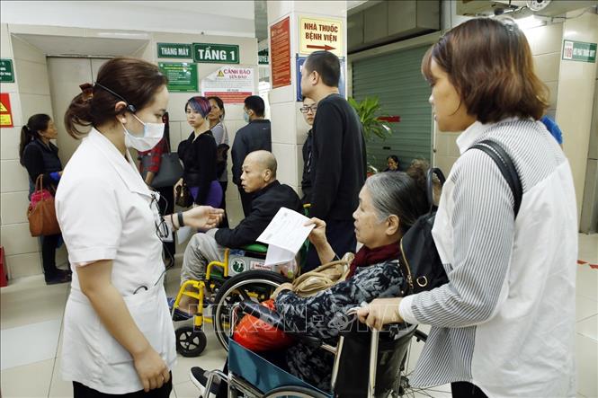 Trong ảnh: Nhân viên công tác xã hội hướng dẫn người bệnh làm thủ tục khám chữa bệnh tại bệnh viện Bạch Mai. Ảnh: Dương Ngọc – TTXVN