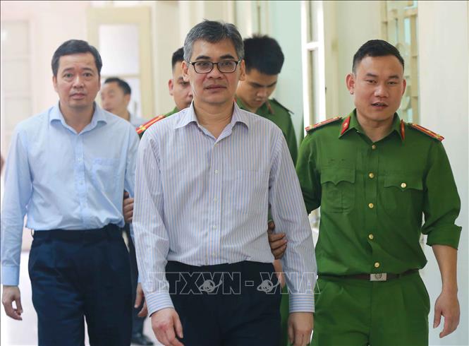 Trong ảnh: Cảnh sát dẫn giải bị cáo Từ Thành Nghĩa (trước, nguyên Tổng Giám đốc VSP) và Võ Quang Huy (sau, nguyên Chánh kế toán VSP) rời phiên tòa sau khi kết thúc. Ảnh: Doãn Tấn - TTXVN