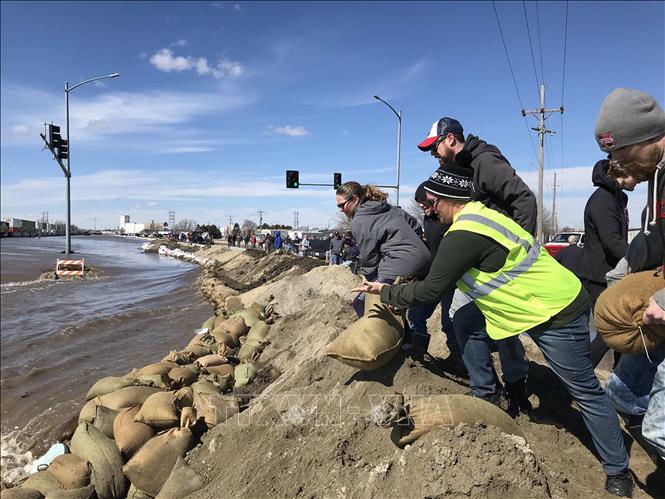 Trong ảnh: Người dân đắp những bao cát ngăn nước lũ  trên một tuyến đường ở Nebraska, Mỹ ngày 19/3. Ảnh: AFP/TTXVN