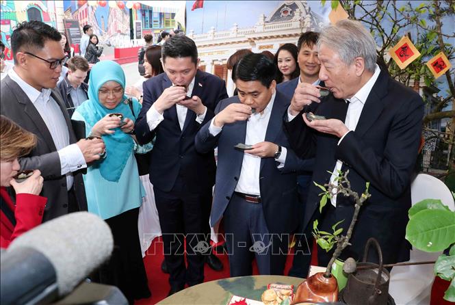 Photo: Chairman of Hanoi People’s Committee Nguyen Duc Chung (2nd R), Singaporean Deputy Prime Minister Teo Chee Hean (R) and delegates enjoy tea at the festival. VNA Photo: Văn Điệp 