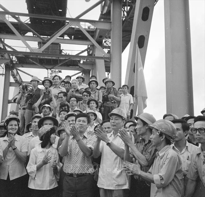 Trong ảnh: 11 giờ ngày 18/10/1983, Bộ trưởng Bộ Giao thông vận tải Đồng Sĩ Nguyên (giữa, áo trắng, đội mũ) cùng các chuyên gia Liên Xô và người lao động Việt Nam thực hiện nghi thức vặn chiếc bu-loong cuối cùng trên công trường xây dựng cầu Thăng Long, nối liền 2 bờ Nam Bắc của công trình mang biểu tượng của tình hữu nghị Việt-Xô này. Ảnh: Vũ Hanh - TTXVN
