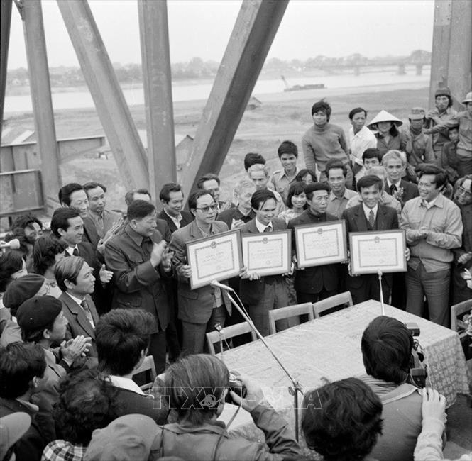 Trong ảnh: Bộ trưởng Bộ Giao thông vận tải Đồng Sĩ Nguyên (người áo sẫm vỗ tay, cạnh người đeo kính nhận bằng khen) trao bằng khen cho 4 đơn vị tham gia xây dựng cầu Chương Dương tại lễ nối liền dầm cầu Chương Dương, ngày 17/2/1985. Thời gian đó, ông là người kiên quyết bảo vệ phương án phải xây dựng cầu Chương Dương khi chúng ta định chỉ làm duy nhất cầu Thăng Long bắc qua sông Hồng tại địa bàn Thủ đô. Ảnh: Bảo Hanh - TTXVN  