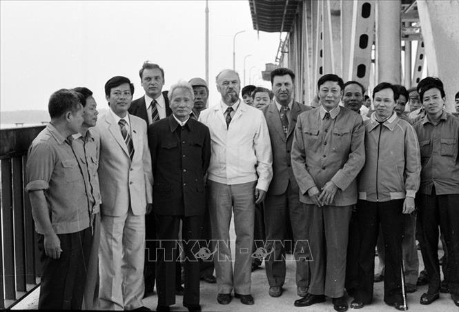 Trong ảnh: Bộ trưởng Bộ Giao thông vận tải Đồng Sĩ Nguyên (thứ ba từ phải sang) cùng các chuyên gia Liên Xô và công nhân Việt Nam đón Chủ tịch Hội đồng Bộ trưởng Phạm Văn Đồng đến thăm công trường xây dựng cầu Thăng Long, ngày 5/11/1983. Ảnh: Xuân Lâm - TTXVN

