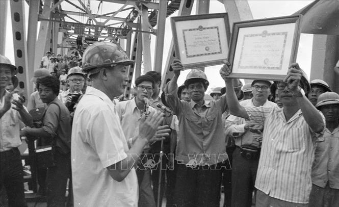 Trong ảnh: Ủy viên dự khuyết Bộ Chính trị, Phó Chủ tịch HĐBT, Bộ trưởng Bộ Giao thông vận tải Đồng Sĩ Nguyên chúc mừng công nhân Việt Nam tại lễ nối liền dầm thép đôi bờ cầu Thăng Long - biểu tượng của tình hữu nghị Việt - Xô, ngày 16/10/1983. Ảnh: Văn Sắc - TTXVN
