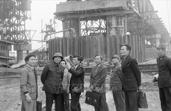 Trong ảnh: Đồng chí Đồng Sĩ Nguyên, Ủy viên dự khuyết Bộ Chính trị, Phó Chủ tịch HĐBT, Bộ trưởng Bộ Giao thông vận tải thăm cán bộ, công nhân Đội 162, Xí nghiệp cầu 16 đang thi công xây dựng cầu Chương Dương, ngày 15/2/1985. Ảnh: Quang Triệu - TTXVN
