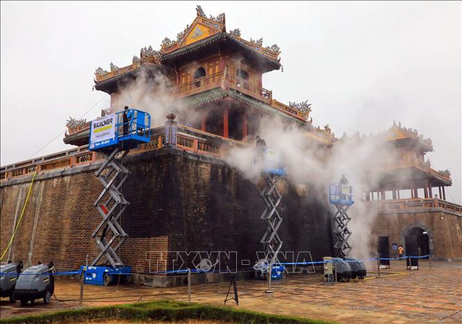 Photo: Foreign experts clean the wall of the Ngo Mon by steam. VNA Photo: Quốc Việt 