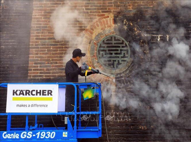 Photo: A foreign expert cleans the wall of the Ngo Mon by steam. VNA Photo: Quốc Việt 