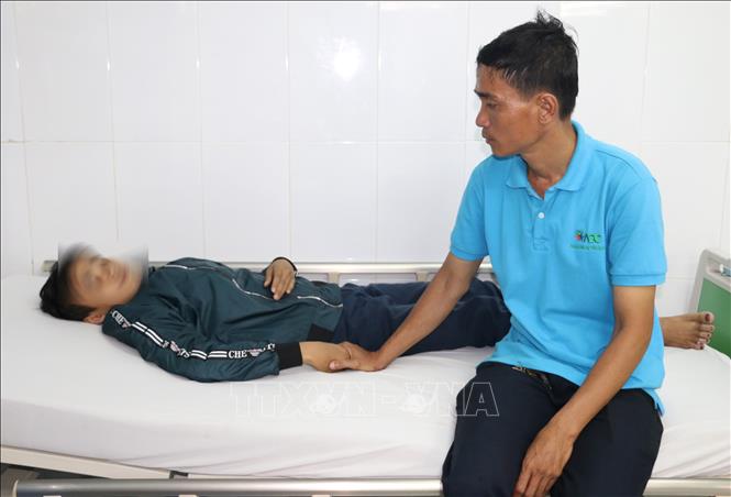 Trong ảnh: Anh Nguyễn Hữu Tri chăm sóc em Thọ tại Phòng cấp cứu Bệnh viện Sản nhi An Giang sau khi bị nhóm bạn học cùng trường đánh hội đồng. Ảnh: Công Mạo-TTXVN