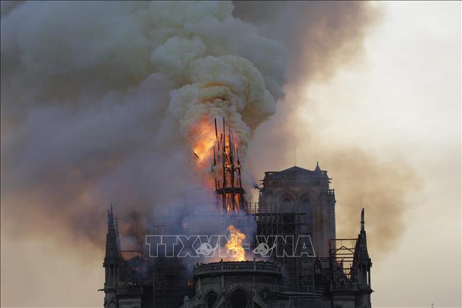 Trong ảnh: Tháp chuông bị sập khi lửa khói bao trùm nóc Nhà thờ Đức Bà ở Paris, Pháp ngày 15/4/2019. Ảnh: AFP/TTXVN