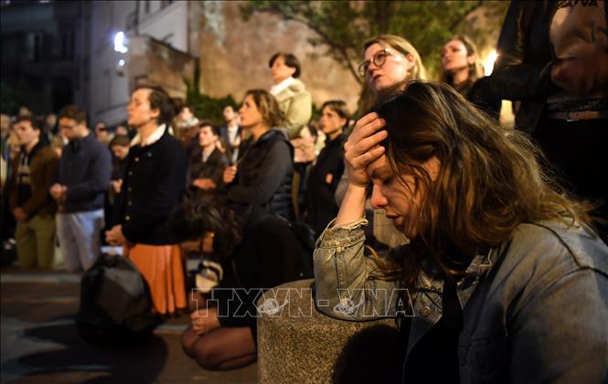Trong ảnh: Người dân cầu nguyện khi chứng kiến vụ hỏa hoạn tại Nhà thờ Đức Bà ở Paris, Pháp ngày 15/4/2019. Ảnh: AFP/TTXVN