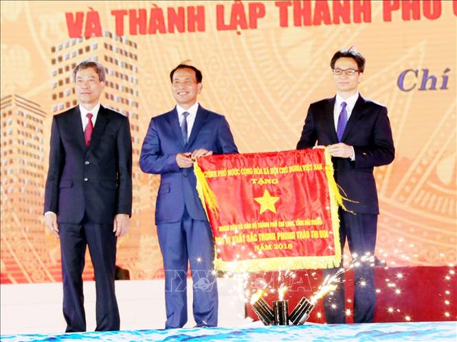 Trong ảnh: Phó Thủ tướng Vũ Đức Đam trao Cờ Thi đua của Chính phủ cho thành phố Chí Linh. Ảnh: Trọng Đức – TTXVN
