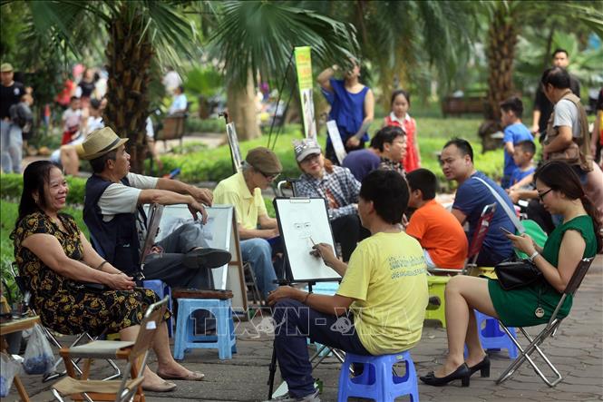 Trong ảnh: Vẽ ký họa chân dung tại phố đi bộ Hồ Gươm thu hút khách. Ảnh: Huy Hùng - TTXVN