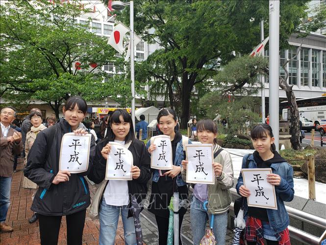 Các học sinh trung học cơ sở ở Tokyo cầm tờ thư pháp ghi chữ Bình Thành - niên hiệu dưới thời Nhật hoàng Akihito. Ảnh: Đào Tùng-TTXVN