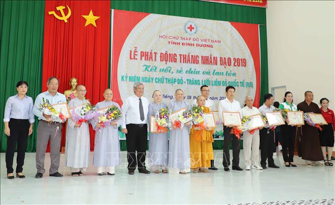 Ông Đặng Minh Hưng ( người đứng giữa ) Phó Chủ tịch UBND tỉnh Bình Dương trao Bảng tấm lòng vàng nhân đạo cho các đơn vị, cá nhân đã ủng hộ nguồn lực cho tháng nhân đạo 2019. Ảnh: Nguyễn Văn Việt-TTXVN