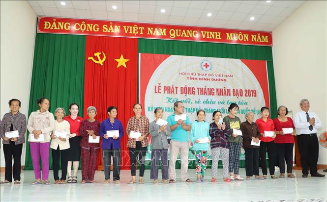 Ông Đặng Minh Hưng ( người đầu tiên bên phải ) Phó Chủ tịch UBND tỉnh Bình Dương trao quà chữ thập đỏ cho người nghèo ở huyện Dầu Tiếng. Ảnh: Nguyễn Văn Việt-TTXVN