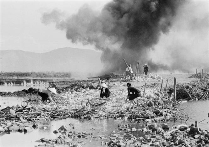 Trong ảnh: Lực lượng dân công hỏa tuyến san lấp hố bom giữa lúc địch bắn phá. Suốt 16 năm, các lực lượng tham gia xây dựng đường Trường Sơn đã ngoan cường vượt qua muôn vàn gian khổ, khó khăn, dưới mưa bom bão đạn, thời tiết khắc nghiệt, vừa mở đường, bám đường vừa nêu cao quyết tâm “sống bám xe bám đường, chết kiên cường dũng cảm”. Ảnh: Hữu Ngôi - TTXVN