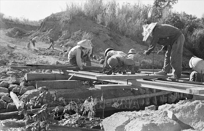 Trong ảnh: Mặc cho máy bay Mỹ điên cuồng đánh phá, chiến sĩ công binh cầu Đ, Quảng Bình vẫn ngày đêm bám đường, bắc cầu cho xe ra tiền tuyến, đảm bảo mạch máu giao thông giữa hậu phương và tiền tuyến, tháng 8/1968. Ảnh: Chí Thành - TTXVN
