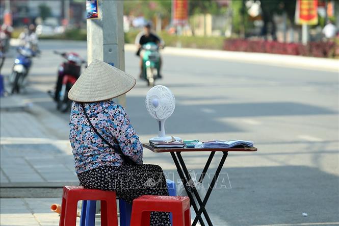 Trong ảnh: Người dân bán vé số dùng quạt tích điện khi ngoài trời nắng nóng. Ảnh: Phan Tuấn Anh - TTXVN