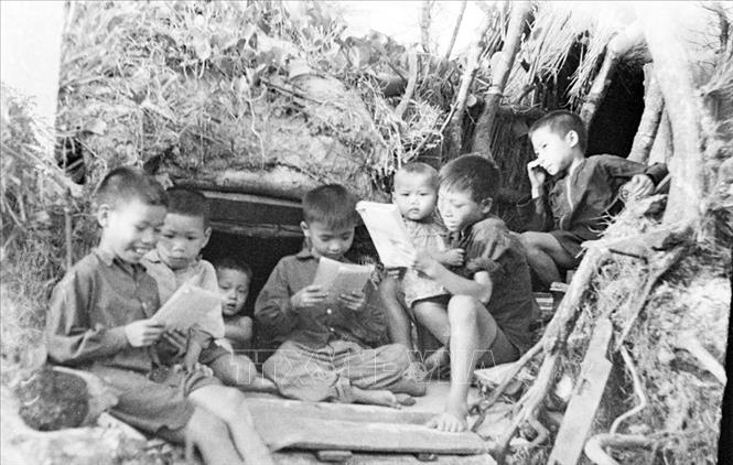 Trong ảnh: Trẻ em học tập bên cửa hầm trú ẩn tại Quảng Bình (năm 1968). Ảnh: Nghĩa Dũng – TTXVN