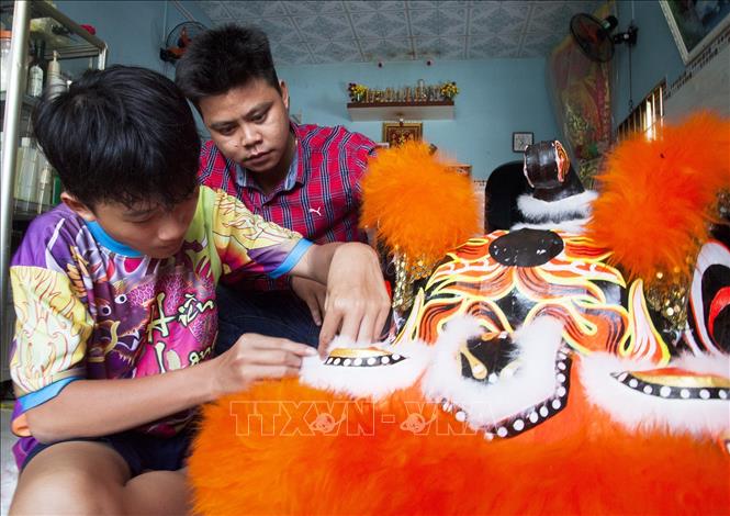 Trong ảnh: Anh Lê Văn Hiền kiểm tra công đoạn gắn lông cho đầu lân. Ảnh: Hồng Đạt - TTXVN
