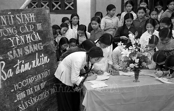 Trong ảnh: Học sinh trường cấp III Yên Hòa, Hà Nội đăng ký phong trào “Ba đảm nhiệm” sau này là phong trào phụ nữ “Ba đảm đang”. Phong trào “Ba đảm đang” do Chủ tịch Hồ Chí Minh đặt tên và Hội Liên hiệp phụ nữ Việt Nam phát động đã tạo nên một khí thế mạnh mẽ trong phong trào thi đua sản xuất, tham gia phục vụ và sẵn sàng chiến đấu, góp phần quan trọng và sự nghiệp xây dựng CNXH ở miền Bắc, giải phóng miền Nam. Ảnh:Thanh Tụng – TTXVN