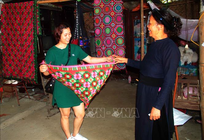 Trong ảnh: Nhiều khách hàng đã tìm đến nhà Nghệ nhân Nông Thị Thược để mua sản phẩm dệt thổ cẩm truyền thống. Ảnh: Chu Hiệu - TTXVN