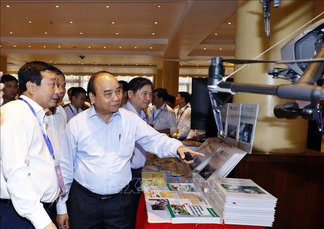 Trong ảnh: Thủ tướng Nguyễn Xuân Phúc và các đại biểu tham quan triển lãm công nghệ phòng chống thiên tai được trưng bày tại hội nghị. Ảnh: Thống Nhất -TTXVN  
