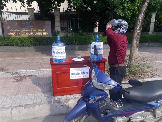  Trong ảnh: Người đi đường được uống nước miễn phí tại Điện lực quận Long Biên. Ảnh: Tiến Hiệp-TTXVN