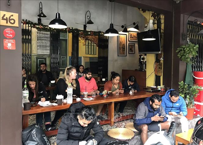 Hà Nội là thành phố bình yên, có sức hấp dẫn lớn đối với du khách, các nhà đầu tư và khách quốc tế không chỉ bởi cảnh đẹp và bề dày văn hóa truyền thống, mà còn ở sự an toàn tuyệt đối, sự thân thiện, hiếu khách của người dân Thủ đô. Trong ảnh: Du khách quốc tế thưởng thức cà phê trên phố Nguyễn Hữu Huân, quận Hoàn Kiếm, trải nghiệm cách sống rất riêng của người Hà Nội: sống trên vỉa hè, ăn cơm trên vỉa hè, nuôi con trên vỉa hè, làm ăn trên vỉa hè. Ảnh: Minh Quyết – TTXVN