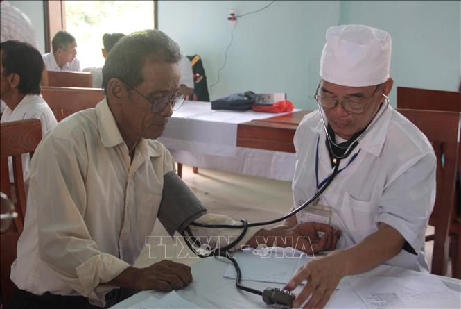 Trong ảnh: Bác sỹ đo huyết áp cho người bệnh. Ảnh: Trịnh Bang Nhiệm - TTXVN