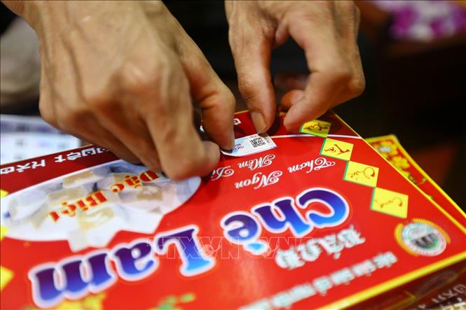 Trong ảnh: Dán tem xác thực nguồn gốc hàng hoá VNPT Check cho sản phẩm Chè lam của làng nghề Thạch Xá (Thạch Thất, Hà Nội). Ảnh: Minh Quyết – TTXVN