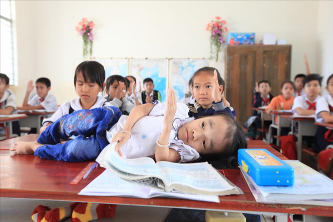 Trong ảnh: Em Võ Thị Yến Nhi, phường Ninh Sơn, thành phố Tây Ninh bị bệnh xương thủy tinh, do ảnh hưởng chất độc da cam/dioxin từ người thân trong gia đình. Em không tự đi lại được nhưng vẫn ham học, hằng ngày được mẹ cõng đến trường và nằm học. Ảnh: Anh Tuấn – TTXVN