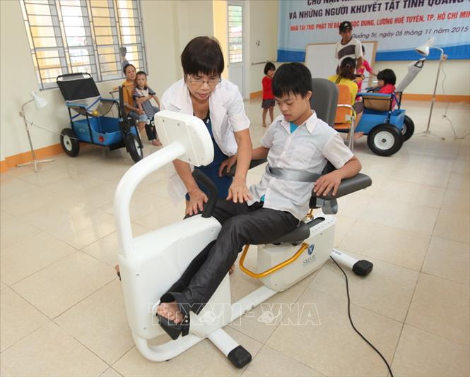 Trong ảnh: Nhân viên Trung tâm Nuôi dưỡng, phục hồi chức năng và dạy nghề cho nạn nhân chất độc da cam tại thành phố Đông Hà, tỉnh Quảng Trị giúp các trẻ là nạn nhân chất độc da cam/dioxin tập phục hồi chức năng (2015). Ảnh: Anh Tuấn - TTXVN