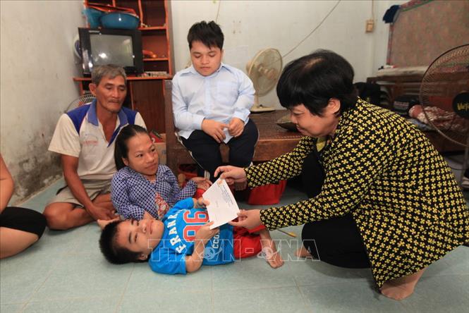 Trong ảnh: Chủ tịch Hội Nạn nhân chất độc da cam/dioxin tỉnh Kiên Giang Trần Thu Vân tặng quà của Hội cho gia đình anh Phạm Văn Bưởi và chị Nguyễn Thị Viễn, xã Mông Thọ A, huyện Châu Thành, tỉnh Kiên Giang, có 3 con bị nhiễm chất độc da cam/dioxin. Ảnh: Anh Tuấn – TTXVN