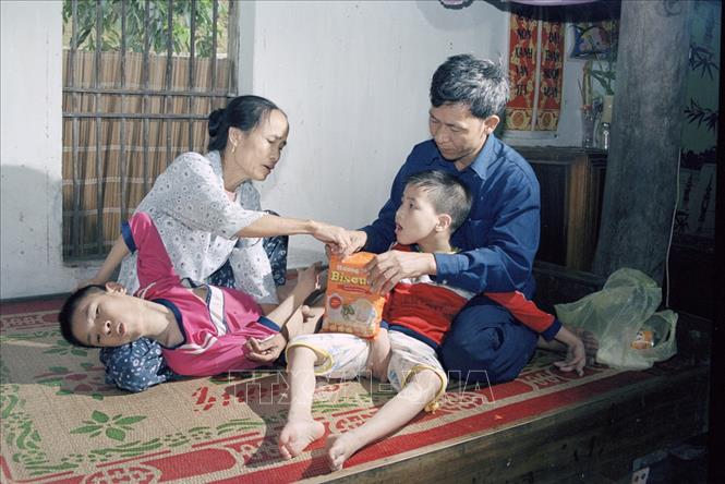 Trong ảnh: Vợ chồng anh Hoàng Nguyên Hòa và chị Nguyễn Thị Ân ở xã Quỳnh Văn, huyện Quỳnh Lưu, tỉnh Nghệ An đều ở chiến trường trở về, có 2 con bị di chứng chất độc da cam/dioxin. Các cháu đều được nhận trợ cấp thường xuyên hàng tháng từ tỉnh (2002). Ảnh: Phùng Triệu - TTXVN