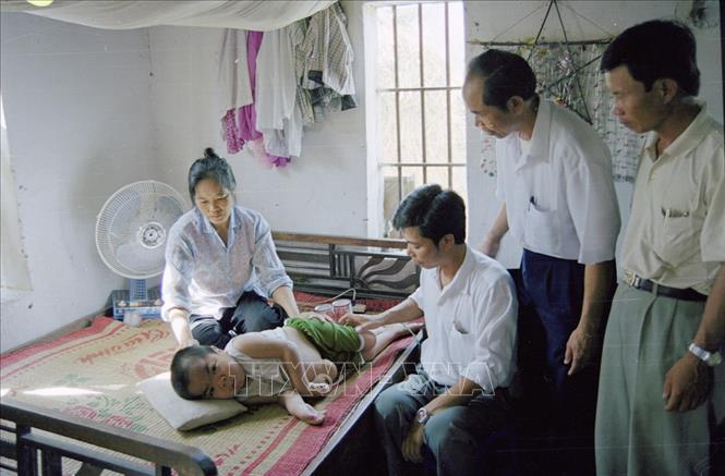 Trong ảnh: Cán bộ xã Hải Thanh, huyện Hải Hậu, tỉnh Nam Định đến thăm, tặng quà cho cháu Lê Xuân Diệu (sinh năm 1990), con anh Lê Xuân Đường, bộ đội chiến đấu ở chiến trường miền Nam, bị dị dạng do nhiễm chất độc da cam/dioxin (1998). Ảnh: Vũ Hanh - TTXVN