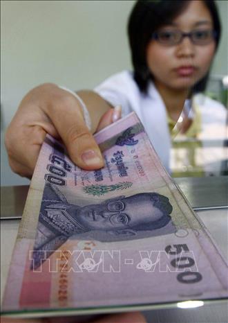 Trong ảnh: Kiểm đồng bath Thái tại một ngân hàng ở Bangkok. Ảnh: AFP/TTXVN