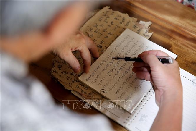 Trong ảnh: Ông Sầm Văn Bình thường xuyên ghi chép, tìm hiểu và cố gắng nắm bắt hết tất cả những tâm linh, phong tục tập quán và chữ viết đồng bào Thái. Ảnh: BÍch Huệ - TTXVN