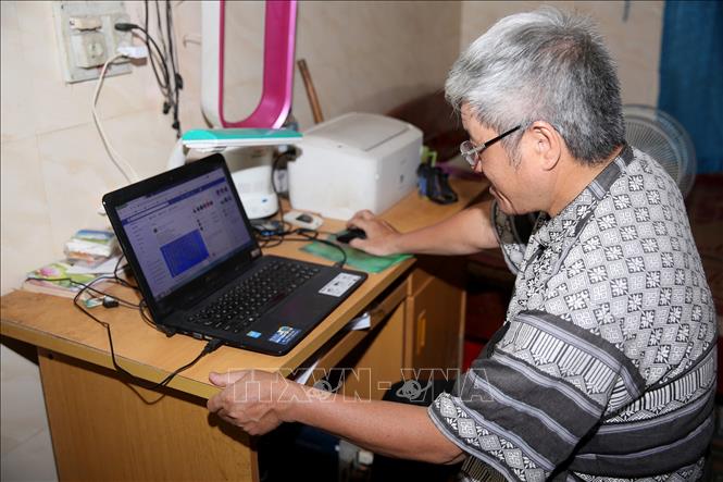 Trong ảnh: Ông Sầm Văn Bình nghiên cứu và thiết kế thành công 5 font chữ Thái cài đặt để đánh chữ Thái trên máy tính. Ảnh: Bích Huệ - TTXVN
