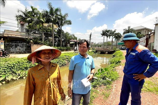 Anh Trung Kiên con trai bà Nguyễn Thị Hoa ( áo xanh ở giữa) trao đổi về việc mẹ hiến căn nhà và đất cho chính quyền cải tạo suối Đồng Tiền. Ảnh: Dương Chí Tưởng-TTXVN