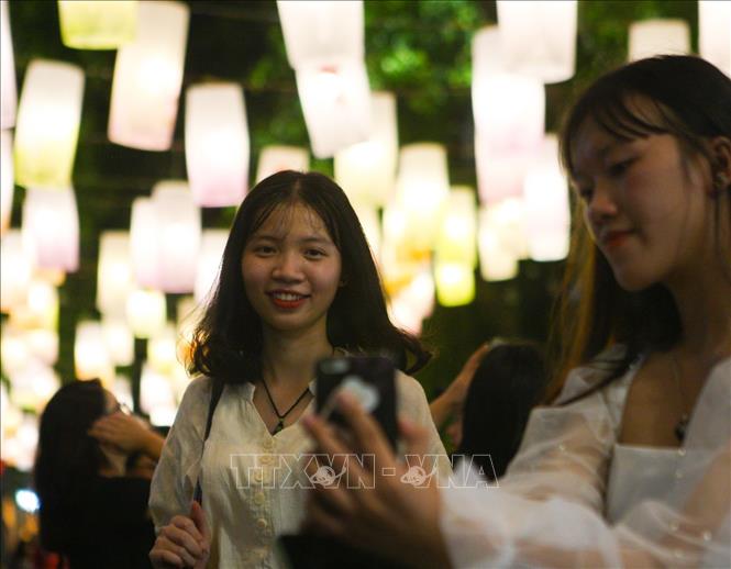 Trong ảnh: Các bạn trẻ say sưa tạo dáng, ghi lại những khoảnh khắc đẹp dưới ánh đèn lồng. Ảnh: Thanh Tùng-TTXVN

