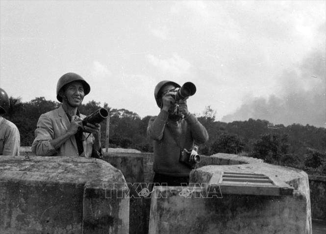 Trong các cuộc kháng chiến thống nhất và bảo vệ Tổ quốc, những phóng viên TTXVN thực sự là các nhà báo – chiến sĩ khi có mặt ở các điểm nóng, các sự kiện lịch sử để ghi lại hình ảnh những khoảnh khắc thiêng liêng, những dấu mốc trọng đại của lịch sử đất nước, để ngày nay, lịch sử TTXVN, lịch sử nhiếp ảnh Việt Nam có được những bức ảnh vô giá, cùng một kho tư liệu ảnh quốc gia đồ sộ. Trong ảnh: Phóng viên ảnh TTXVN trên nóc tòa nhà 18 Trần Hưng Đạo để chụp ảnh máy bay Mỹ bị bắn cháy trên bầu trời Hà Nội, tháng 12/1972. Ảnh: TTXVN